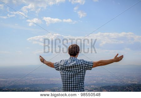 A Young Man Overlooking The Landscape From The Hill With His Arms Wide Spread