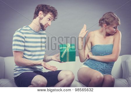 Young Man Giving Offended Woman Gift Box