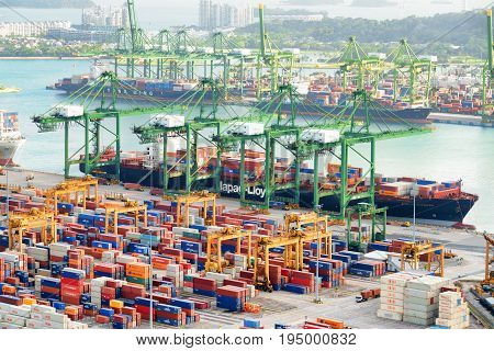 Singapore - February 17 2017: Amazing view of a container terminal at the Port of Singapore. Cargo ships docked in harbor. Ship-to-shore gantry cranes loading and unloading vessels at shipping yard.