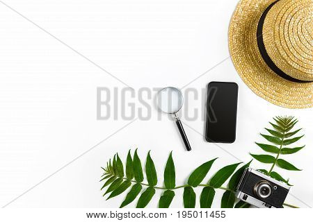 Straw hat with green leaves and old camera on white background, Summer background. Top view. Copy space. Still life. Flat lay