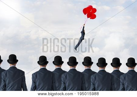 business freedom concept businessman flying away from a crowd of businessmen with balloons
