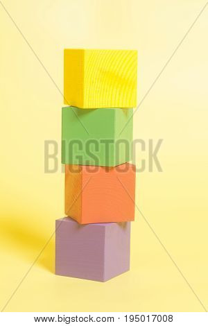 Coloured wooden cubes on yellow background .