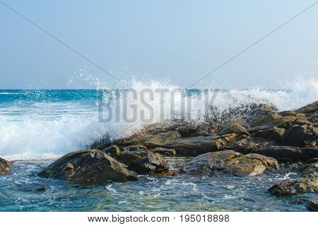 Waves of the ocean break into white splashes of dark stones. Southern province. Sri Lanka