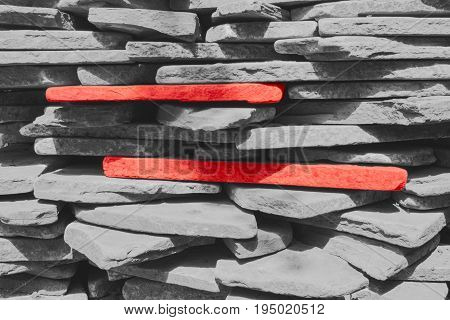 Two red stones among the gray stones which are stacked one on the other.