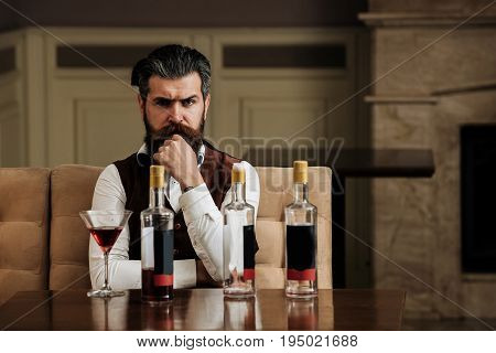 Man Sitting At Table With Three Bottles And Glass