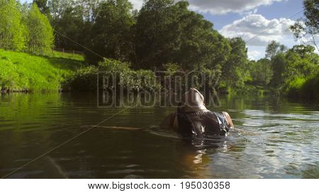 A young woman in a black bathing suit bathing in a forest river