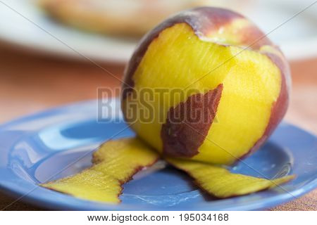 fresh peach peeled on a colored dish