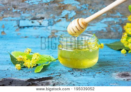 linden honey in glass on a blue background with a linden flowers and linden honey. Fresh linden