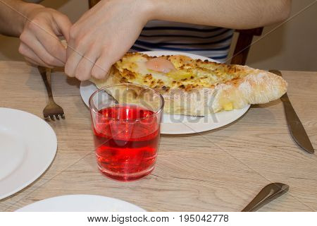 Khachapuri on ajarski - recipe of Georgian cuisine. Adjarian Georgian national dish Khachapuri bread with cheese and egg on a plate in a cafe