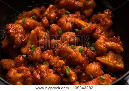 Gobi Manchurian dry - Popular street food of India made of cauliflower florets in a frying pan, selective focus