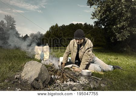 Vagabond young man wake up in park near illegal fire place