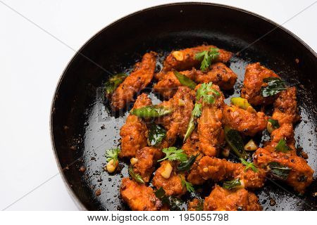 Chicken 65 - spicy deep fried Bar appetizer or quick snack from India in a frying pan over white background, selective focus