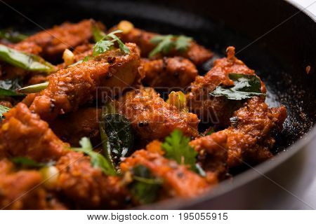 Chicken 65 - spicy deep fried Bar appetizer or quick snack from India in a frying pan over white background, selective focus