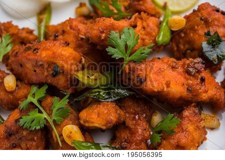 Chicken 65 - spicy deep fried Bar appetizer or quick snack from India in a bowl or plate over white background, selective focus