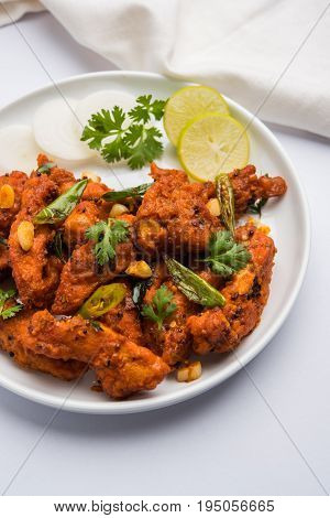 Chicken 65 - spicy deep fried Bar appetizer or quick snack from India in a bowl or plate over white background, selective focus