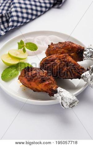 Chicken Tangri kabab or kebab - three Chicken leg pieces marinated with red sauce then grilled and served with salad. It can be served with green chutney