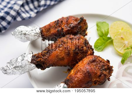Chicken Tangri kabab or kebab - three Chicken leg pieces marinated with red sauce then grilled and served with salad. It can be served with green chutney