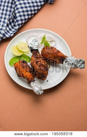 Chicken Tangri kabab or kebab - three Chicken leg pieces marinated with red sauce then grilled and served with salad. It can be served with green chutney