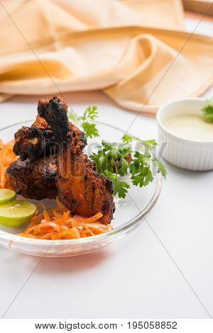 Chicken Tangri kabab or kebab - three Chicken leg pieces marinated with red sauce then grilled and served with salad. It can be served with green chutney