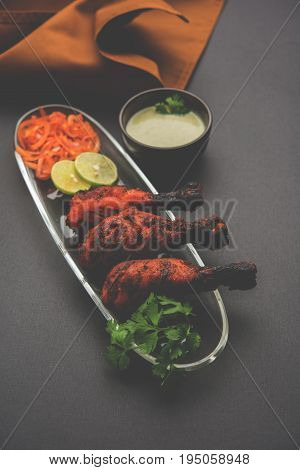 Chicken Tangri kabab or kebab - three Chicken leg pieces marinated with red sauce then grilled and served with salad. It can be served with green chutney