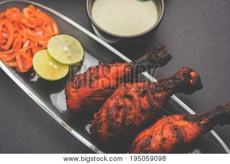 Chicken Tangri kabab or kebab - three Chicken leg pieces marinated with red sauce then grilled and served with salad. It can be served with green chutney