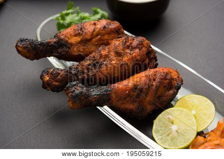 Chicken Tangri kabab or kebab - three Chicken leg pieces marinated with red sauce then grilled and served with salad. It can be served with green chutney