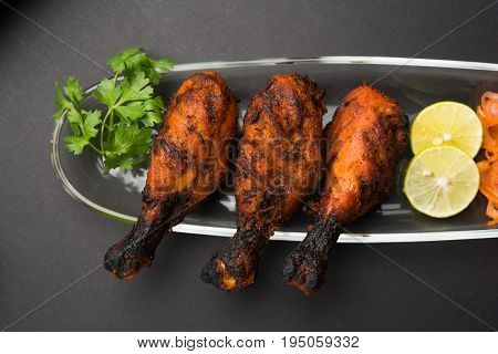 Chicken Tangri kabab or kebab - three Chicken leg pieces marinated with red sauce then grilled and served with salad. It can be served with green chutney