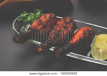 Chicken Tangri kabab or kebab - three Chicken leg pieces marinated with red sauce then grilled and served with salad. It can be served with green chutney