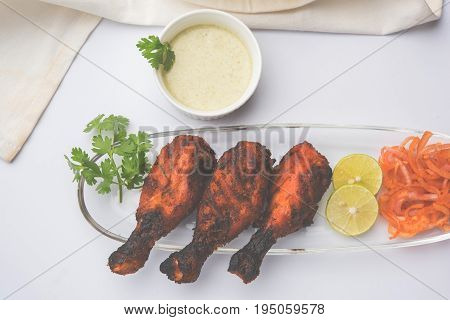 Chicken Tangri kabab or kebab - three Chicken leg pieces marinated with red sauce then grilled and served with salad. It can be served with green chutney