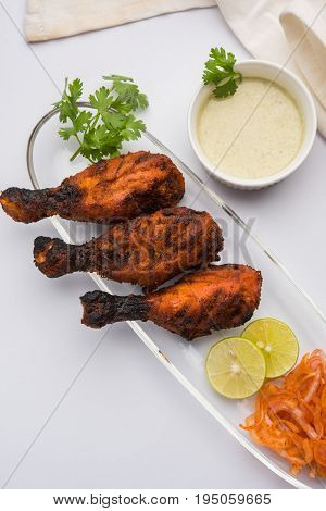Chicken Tangri kabab or kebab - three Chicken leg pieces marinated with red sauce then grilled and served with salad. It can be served with green chutney