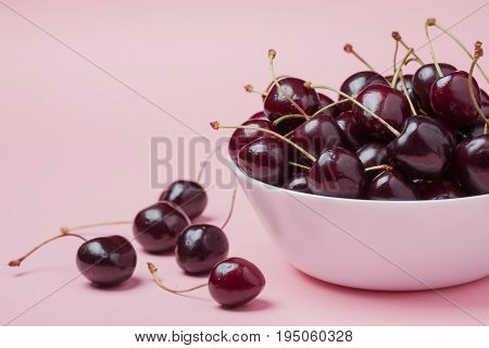 White Bowl Of Fresh Red Cherries On A Pink Background. Copy Space. Close-up