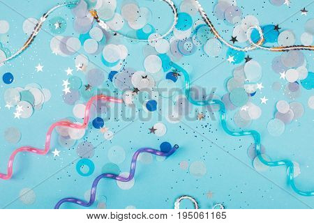 Blue pastel festive background with sparkles and confetti. Flat lay style.