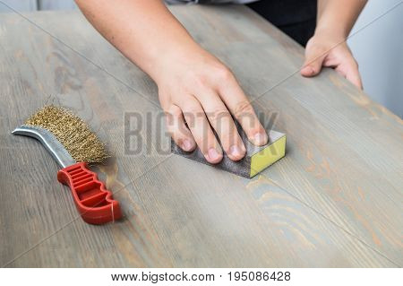 Sanding the wood table top. Male hands using sand cloth for finishing distressed pine wood table top