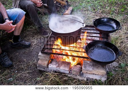 Cooking dinner in iron kettle at bonfire. Bonfire cooking. Selective focus blur