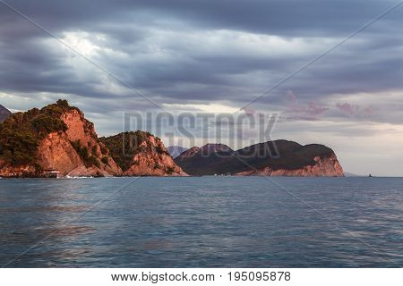 Sunset in Montenegro on the sea, Petrovac, red cliff, clouds
