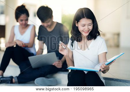Asian student do report read a book and home work togather at library in university