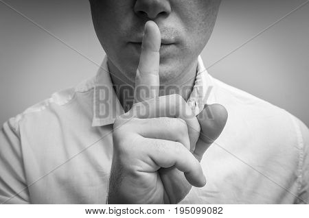 Attractive man with finger on lips making silence gesture. Shh!!!