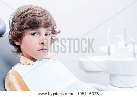 Little Caucasian Boy Sitting In Chair In Dentist Office