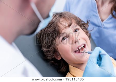 Dentist Examining Teeth Of Little Boy In Dental Clinic