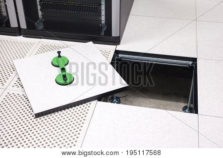 High angle view of lifted floor tile with vacuum suction cups in datacenter