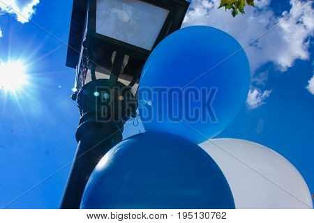 Composition of some balloons and a street lamp looking at the blue sky