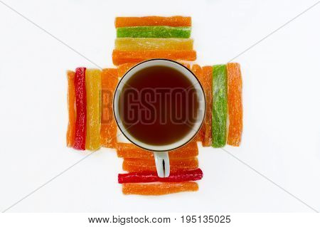 Still Life - Black Tea In A Cup, Around It Are Lined Multi-colored Pineapple Candied Fruits On A Whi