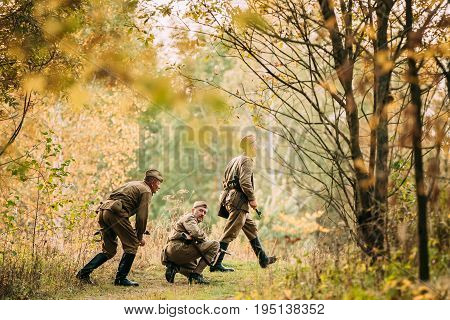 Dyatlovichi, Belarus - October 1, 2016: Group Of Reenactors Men Dressed As Russian Soviet Red Army Infantry Soldiers Of World War II Marching In Autumn Field With Weapons At Historical Reenactment
