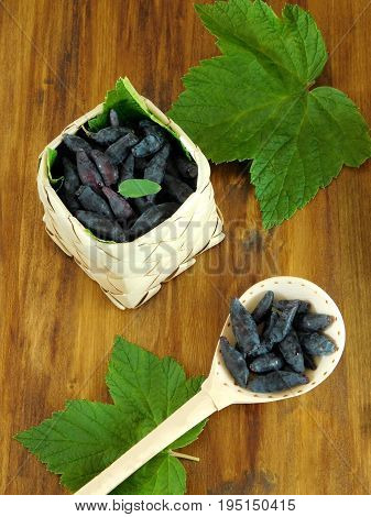 Honeysuckles in a wicker basket and in a wooden spoon on a wooden background
