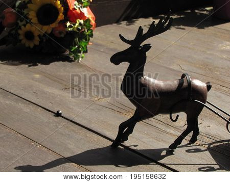 Wooden deer on wooden floor and behind flowers