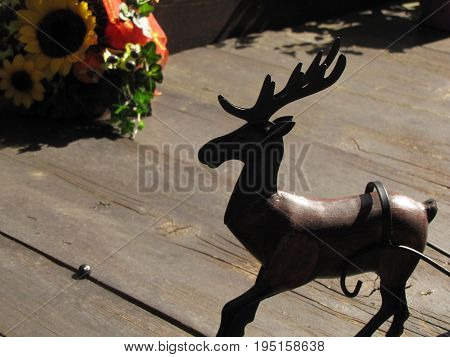 Wooden deer on wooden floor and behind flowers