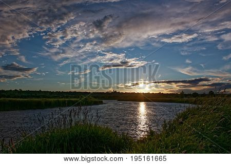 Beautiful shades and clouds in the sky are reflected in the river surface at the time of sunset.