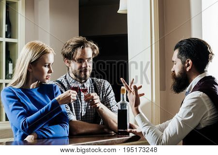 Couple in love and bartender at bar. Girl or woman and man or macho sharing bottle of wine and talking to barman at counter. Date and dating. Alcohol appetizer and aperitif. Addictive and convive