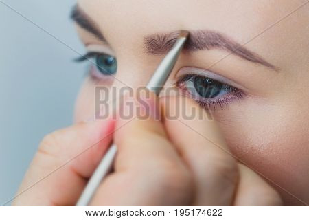 Woman With Blue Eyes Getting Makeup On Brows