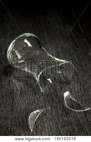 Broken glass glass and shards on a gray wooden background. Low key. Side view.